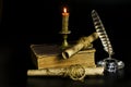 Documents in scrolls, a burning candle, an old book, a glass inkwell with a pen on a black background