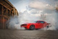 Dodge Challenger SRT Hellcat shrouded in smoke from its burning tires.