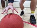 Dodgeball player picking up a large red dodge ball in a sportshall