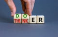 Doer or thinker symbol. Concept words Doer or thinker on wooden cubes. Businessman hand. Beautiful grey table grey background.