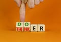 Doer or thinker symbol. Concept words Doer or thinker on wooden cubes. Businessman hand. Beautiful orange table orange background