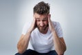 Does anyone have a headache tablet. a young man with a headache holding his head while sitting on a chair in the studio.