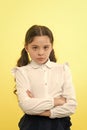 She does not agree with you. Girl serious face offended yellow background. Kid unhappy looks strictly. Girl school