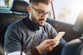 He doesnt need his desk to get work done. a young designer using a cellphone in a car. Royalty Free Stock Photo