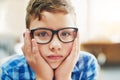 He doesnt want to be here. Portrait of a young boy looking stressed while being seated inside of a classroom during the