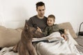 Dog as family member. Mexican hairless, xoloitzquintle. Adult dog on the bed at home, with man and little boy. Natural Royalty Free Stock Photo
