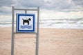 Dog beach sign with sand and breaking waves in the background. Message post, billboard with sign allowing dogs being at the beach Royalty Free Stock Photo