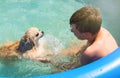 A dog with a boy bathe in the pool on a summer sunny day