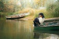 Dog and cat in a boat on the lake in autumn. Friendly pets in nature. Royalty Free Stock Photo