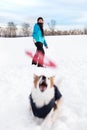 Dog is catching a flying frisbee, laughing woman in the back