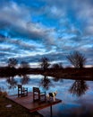 A dog in a coat looks out over a calm river on a crisp winter morning Royalty Free Stock Photo