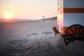 A dog enjoys a beach sunset, nestled by a lifeguard stand