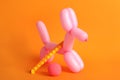 Dog figure made of modelling balloon and chinese finger trap on orange background Royalty Free Stock Photo