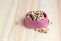 Dog food, bone-shaped biscuits in a pink plastic bowl, top view Royalty Free Stock Photo