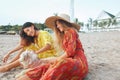 Dog-Friendly Beach. Women In Boho Dresses And Straw Hat With Cute Puppy On Sandy Coast