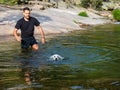 Dog handler teaching puppy to swim alone in lagoon Royalty Free Stock Photo