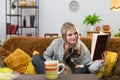 A girl at home in the living room is reading a book with her dog. Multi-breed dog.