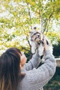 Dog owner and her pet. Happy girl holds with hands up her cute little puppy, feeling happy and expresses love to the dog. Outdoor Royalty Free Stock Photo