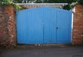 Dog peeks out under large blue wooden gate Royalty Free Stock Photo