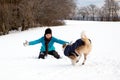 Dog is running to a happy young woman, snowy landscape at the winter season