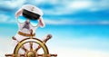 Dog sailor holds ship steering wheel in the sea background.