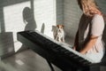 The dog sits and watches as the owner plays the synthesizer