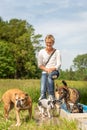 Dog sitter is resting with many dogs by the water. Dog walker with different dog breeds in the beautiful nature
