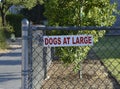 Dogs at Large Metal Sign on Chain Link Fence Royalty Free Stock Photo