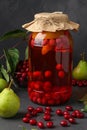 Dogwood compote with pears in jar on dark background, vertical orientation