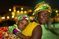 African mother carrying her daughter on her back in traditional African tribe costumes with blurred background