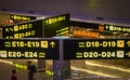 Interior of international airport in Doha, Qatar, with flight signs and passengers. Gates information boards with arrows.