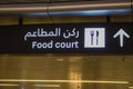 Sign with text `food court` in English and Arabian in airport in Doha. Interior of international airport in Doha, Qatar.