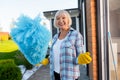 Beaming blonde-haired elderly lady doing cleaning near summer house