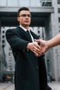 Doing handshake. Businessman in black suit and tie is outdoors in the city Royalty Free Stock Photo