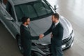 Doing handshake. Two businessmen are working together in the car showroom Royalty Free Stock Photo