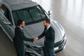 Doing handshake. Two businessmen are working together in the car showroom Royalty Free Stock Photo