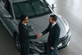 Doing handshake. Two businessmen are working together in the car showroom Royalty Free Stock Photo