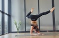 Doing headstand. Young woman in sportive wear and with slim body have fitness yoga day indoors