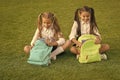 Doing homework better outdoors. Small children do homework ongreen grass. Little girls pick up homework diary from bag Royalty Free Stock Photo