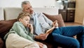 Doing homework together. Grandad and grandson sitting on sofa in the living room and reading book together Royalty Free Stock Photo