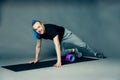 He doing leg exercise by dint of roller for myofascial relaxation on a gray Royalty Free Stock Photo