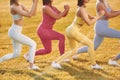 Doing legs exercises. Group of women have fitness outdoors on the field together Royalty Free Stock Photo
