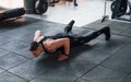 Doing push-ups. Young sportive strong man in black wear have workout day in gym Royalty Free Stock Photo