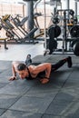 Doing push-ups. Young sportive strong man in black wear have workout day in gym Royalty Free Stock Photo
