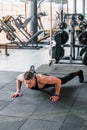 Doing push-ups. Young sportive strong man in black wear have workout day in gym Royalty Free Stock Photo