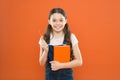 Doing research. literature lesson. back to school. happy little girl with notebook. school girl read book on orange