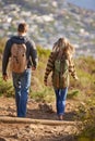 Doing it side by side. Rear view shot of a young couple walking down a hiking trail. Royalty Free Stock Photo