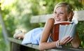 Doing some light reading. Pretty young woman lying on a bench and reading her book outdoors. Royalty Free Stock Photo