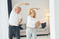 Doing stretching. Senior man and woman is together at home Royalty Free Stock Photo