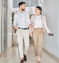 Doing their business on the move. Full length shot of two young businesspeople talking as they walk through a corridor Royalty Free Stock Photo